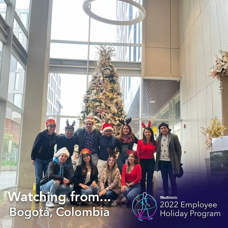 Team in front of a Christmas tree in a "Watching from Bogota, Colombia" frame