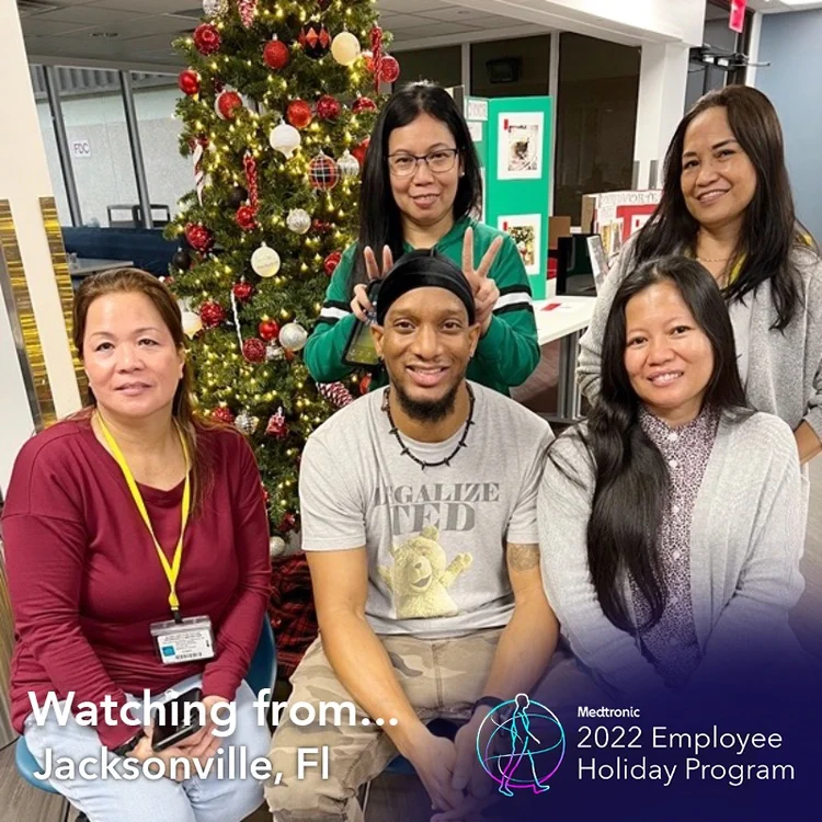Employees by a Christmas tree in a "Watching from Jacksonville, FL" frame