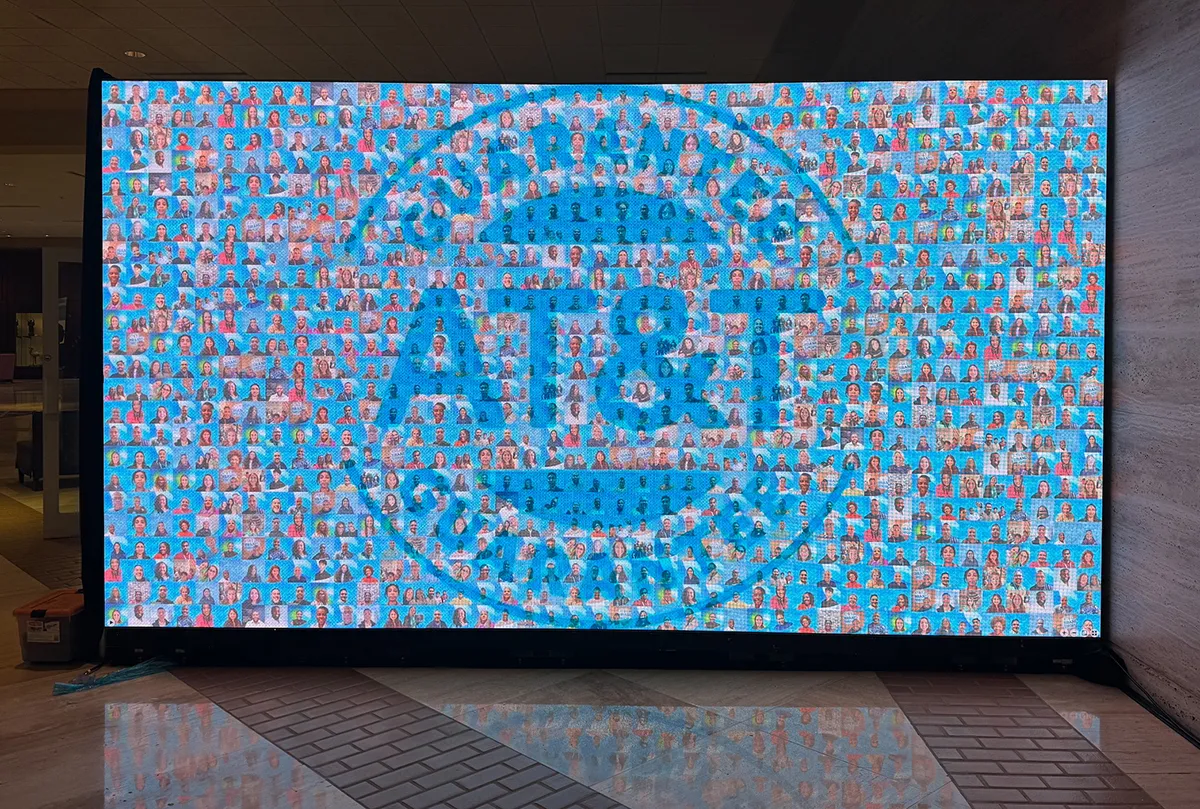 extra large digital display screen with a branded photo mosaic in the middle of an event venue