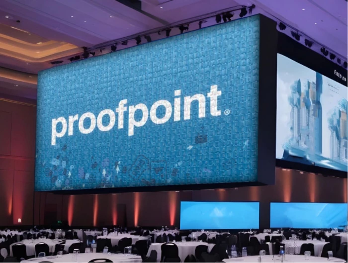 Proofpoint branded live photo mosaic displayed on a large screen at a corporate conference event