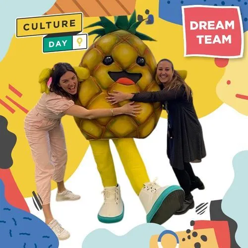 Photo booth snapshot of two guests hugging a pineapple mascot on a Culture Day Dream Team frame