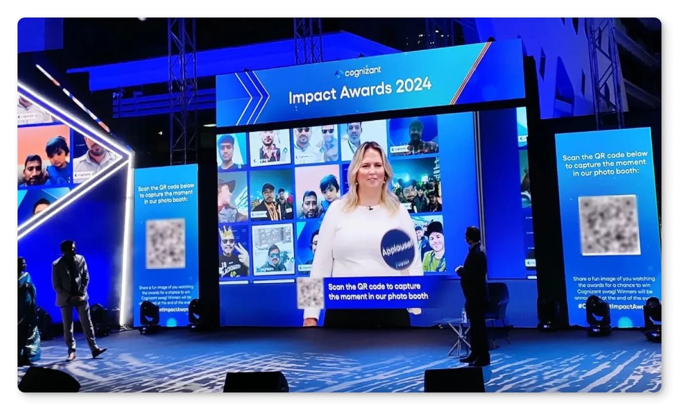 A live gallery of guest photos on a giant LED screen behind a presenter at a corporate awards show, with side screens inviting the audience to take part